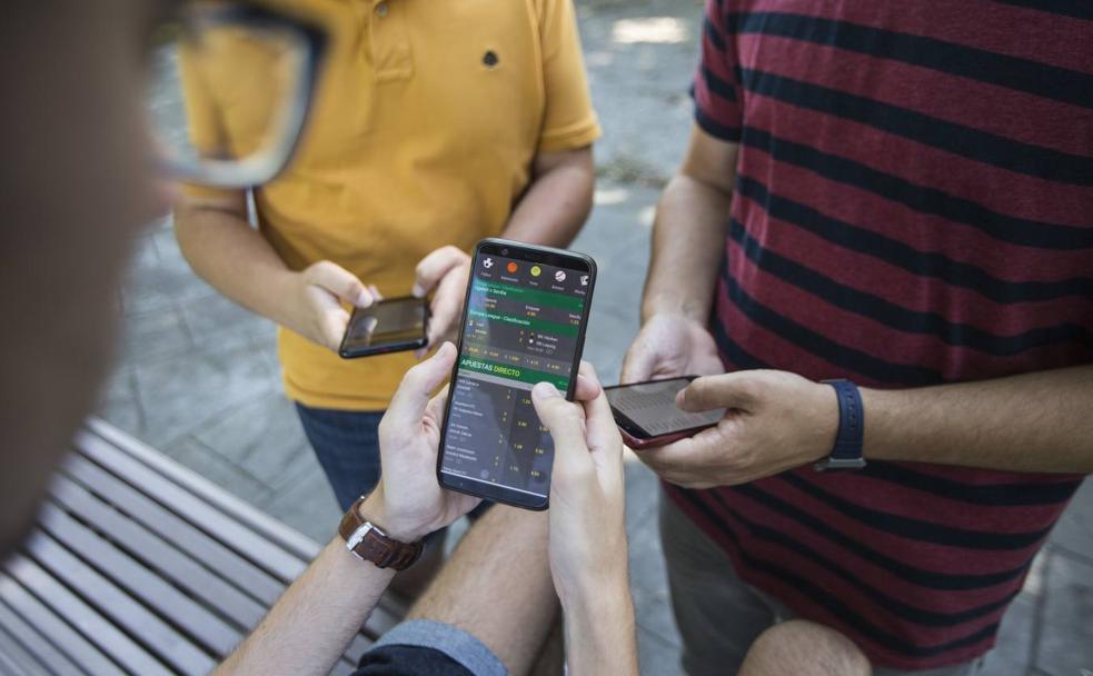 Un grupo de jóvene apuesta desde el teléfono móvil.