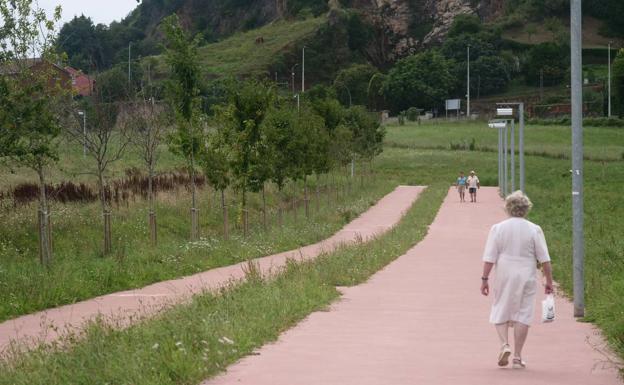 Una señora pasea por el camino peatonal del parque de La Remonta.