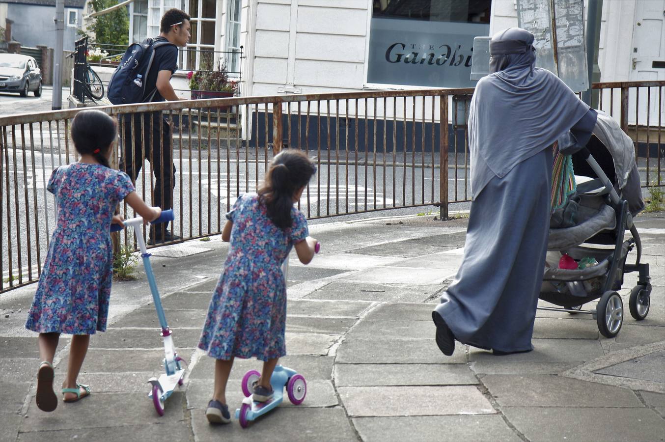 Una mujer musulmana vestida con el típico niqab observa a sus dos hijas vestidas al estilo occidental en una calle de Exeter. 