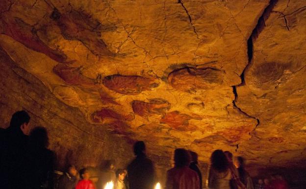 Visitantes del Museo Altamira contemplan la neocueva, con la luz original.