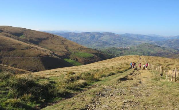 Imagen principal - Arriba, los senderistas bajando a Llerana. Abajo, pasando por el molino de Rubionzo y durante un momento de la ruta. 