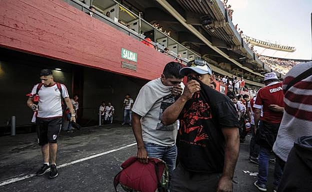 Aficionados de River se cubren la cara por efecto de los gases lanzados en las inmediaciones del Monumental. 