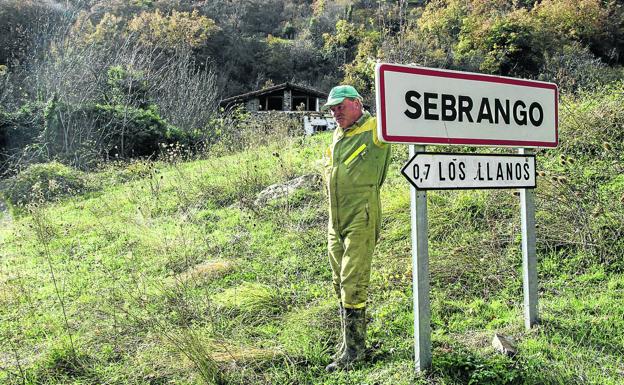 Marcos González, vecino de Sebrango, posa junto al cartel del pueblo abandonado. 