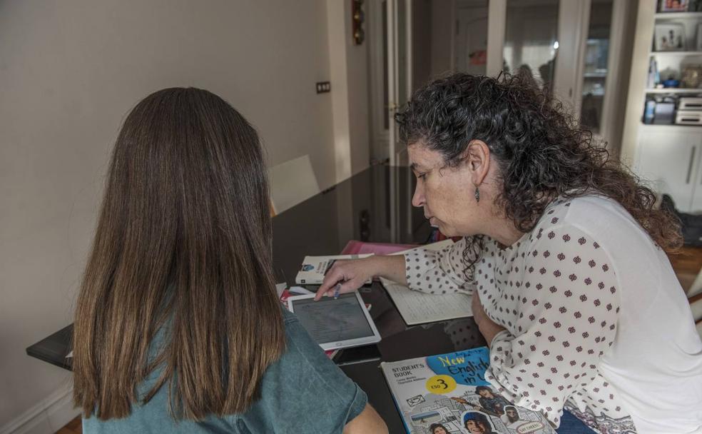 Lucía, de espaldas, estudiante de 3º de ESO, atiende a su profesora de Lengua, María Sánchez, que acude a su casa dos veces por semana, de 12 a 14 horas para la clase