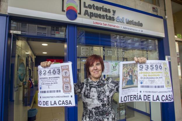 La lotera María del Carmen Pastora, de la administración 24 de Santander, muestra con euforia dos de sus números a la venta.