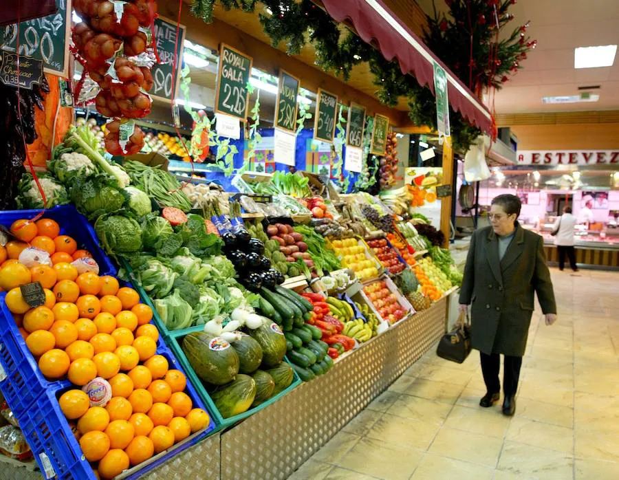 Una clienta pasa ante un puesto de frutería del Mercado de Torrelavega.