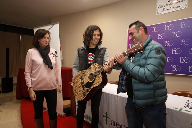 La presidenta de la asociación, Ana Barca, Rulo y el comprador de la guitarra, Fran Portal