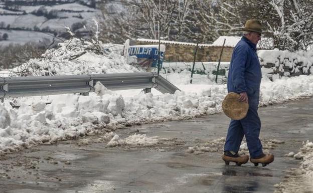 Un vecino de San Martín de Hoyos (Valdeolea) cruza una carretera afectada por la nieve que cayó ayer al sur de Cantabria.