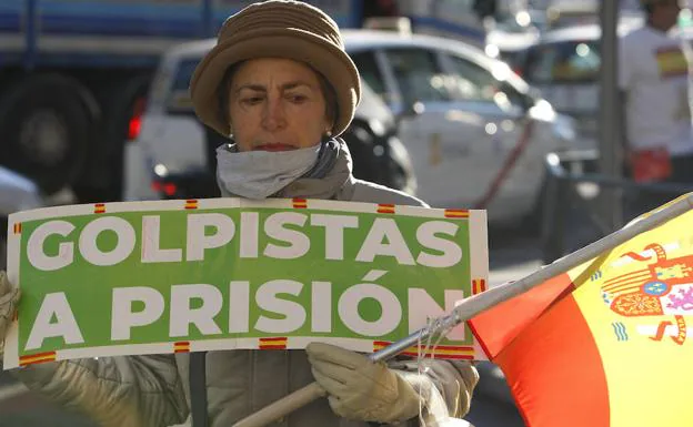 Una mujer sujeta un cartel y una bandera de España en las inmediaciones del Tribunal Supremo, donde hoy empieza el juicio del 'procés'.