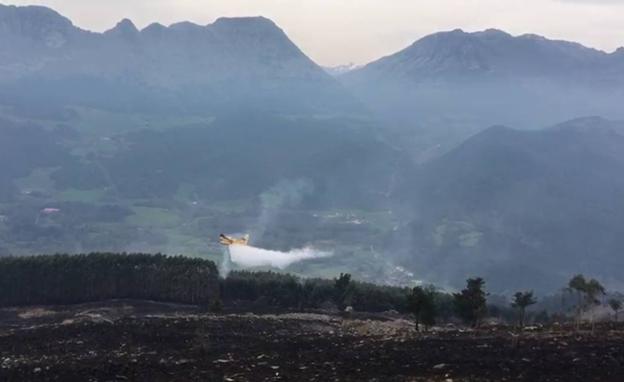 Paisaje quemado de Ramales, con los hidroaviones soltando el agua que han ido a recoger a la bahía de Santander-