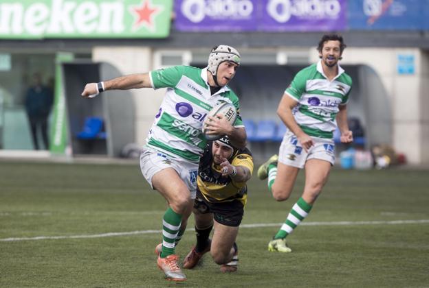 Mañero trata de eludir el placaje de un rival del Burgos ante la mirada de Nacho Poet.