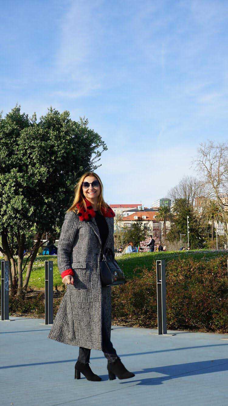 Cristina Rubalcaba combina un pitillo, botines de tacón y bolso bandolera con un abrigo muy especial, de estampado de cuadros en tejido Príncipe de Gales, con cuello de pelo rojo y topos.