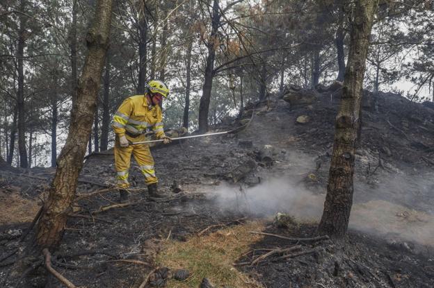 Un bombero apaga rescoldos del incendio del Monte Dobra.