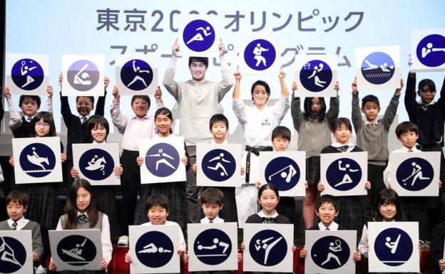 Atletas y estudiantes japoneses exhiben los pictogramas deportivos de Tokio 2020. 