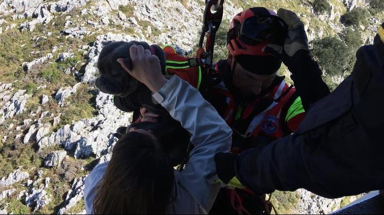 Un miembro del equipo del helicóptero medicalizado del Gobierno de Cantabria iza a una de las mujeres y al perro.