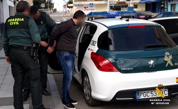 Los agentes meten en el coche a uno de los detenidos en Suances.