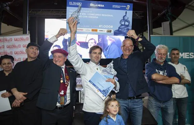 El presidente de la Cofradía de la Anchoa de Cantabria, Tino Sampedro, y Pedro López, de El Diario, sostienen el talón que recibe Sebastián Larralde, ganador del concurso. Abajo, su hija Valentina.