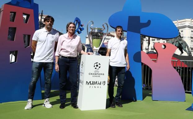 Imagen principal - Arriba, los exfutbolistas Morientes y Solozabal y la primera teniente de alcalde en funciones de Madrid, Marta Higueras, posan con la Champions en la Plaza Mayor. En las imágenes inferiores, dos aficionados del Liverpool, junto al trofeo. 