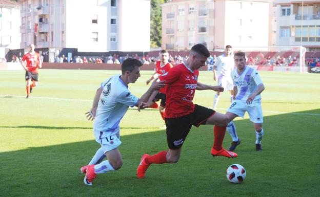 Simón, del Laredo, conduce la pelota ante la presión de un rival. 