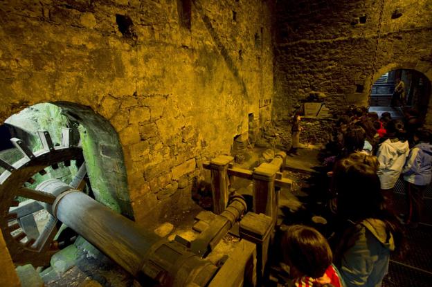 Un grupo de visitantes contempla el interior de la Ferrería de Cades. 