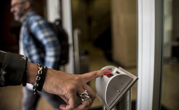 Una empleada utiliza el control dactilar para registrar la entrada a su puesto de trabajo.