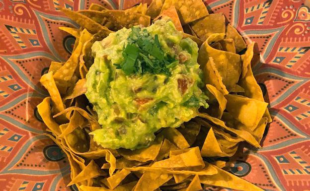 Imagen principal - Totopos de maíz caseros con guacamole, tacos al pastor y enchiladas mixtas de pollo, con salsa verde y roja.