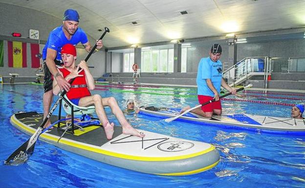 El monitor y director de una escuela de surf, Sergio García, ayuda a un alumno durante una de las clases prácticas desarrolladas en la piscina de La Lechera. 