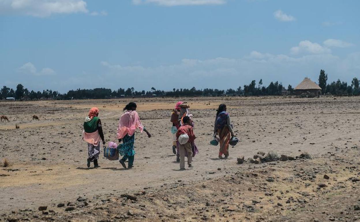 Un grupo de mujeres y niños etíopes abandonan sus casas.
