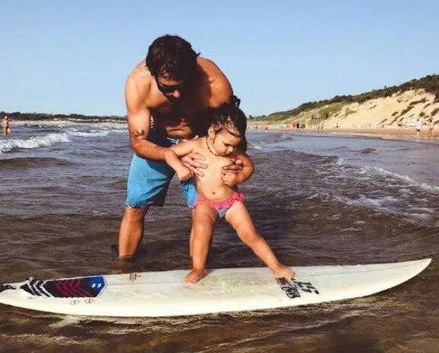 India con su padre disfrutando de las olas.