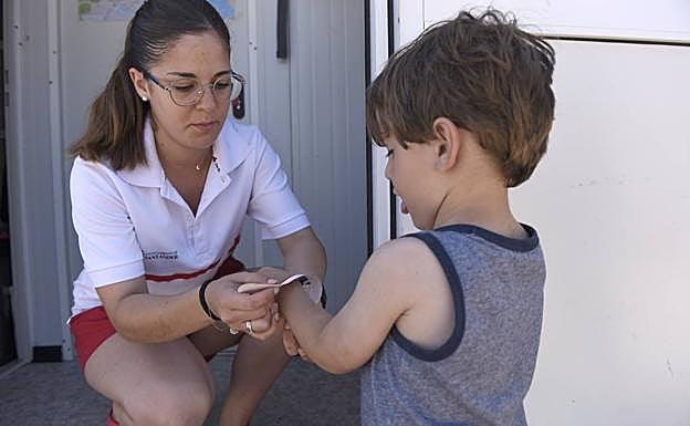 El pequeño David, de dos años, se pone por primera vez la pulsera de Cruz Roja. 