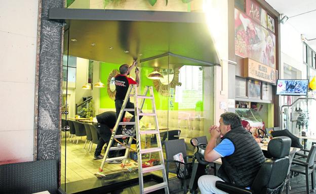 Un operario realiza los trabajos de reparación de la puerta de la cafetería. 