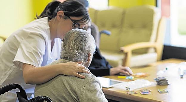 Una trabajadora de una residencia de mayores atiende a una usuaria. :