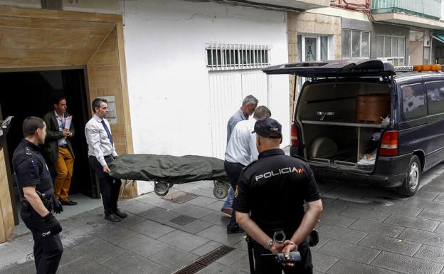 Los servicios funerarios retiran el cadáver de la víctima. 