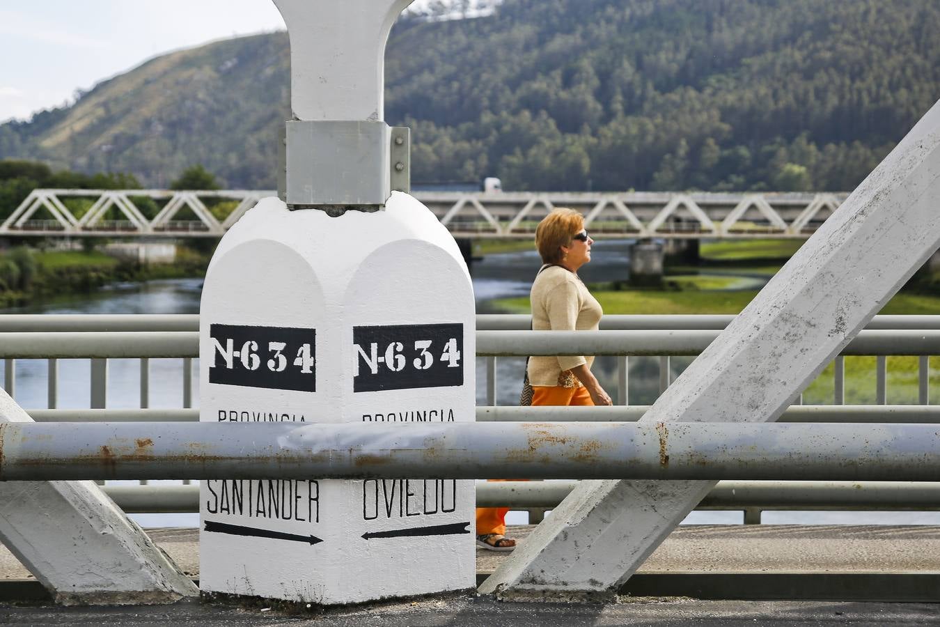 Una mujer atraviesa el límite provincial entre Asturias (Bustio) y Cantabria (Unquera).
