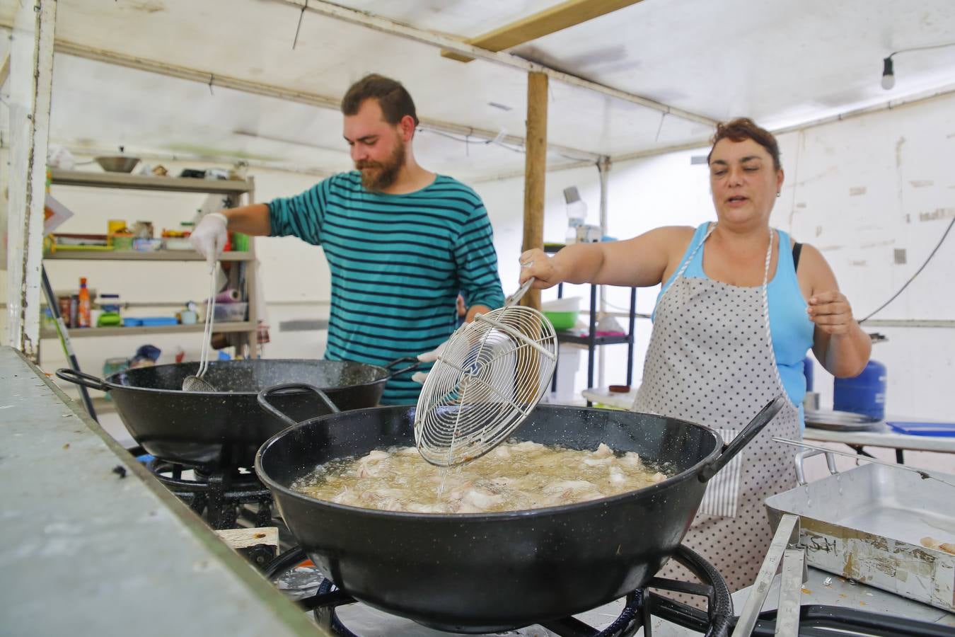 Los cocineros frien alitas de pollo para 120 personas. De primero, ensalada de pasta.