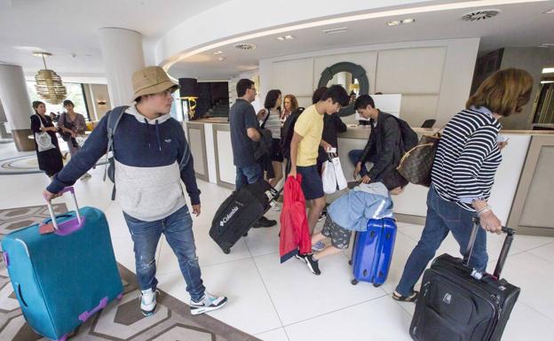 Imagen principal - 1. Una familia se dirige a su habitación tras su llegada, ayer por la mañana, al Hotel Bahía de Santander. | 2. avier, el botones del Hotel Santemar, organiza el equipaje de varios huéspedes. | 3. Los recepcionistas del Hotel Santemar de Santander atienden la llegada de varios clientes. 