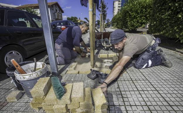 Dos operarios del Ayuntamiento de El Astillero reparando aceras del municipio.