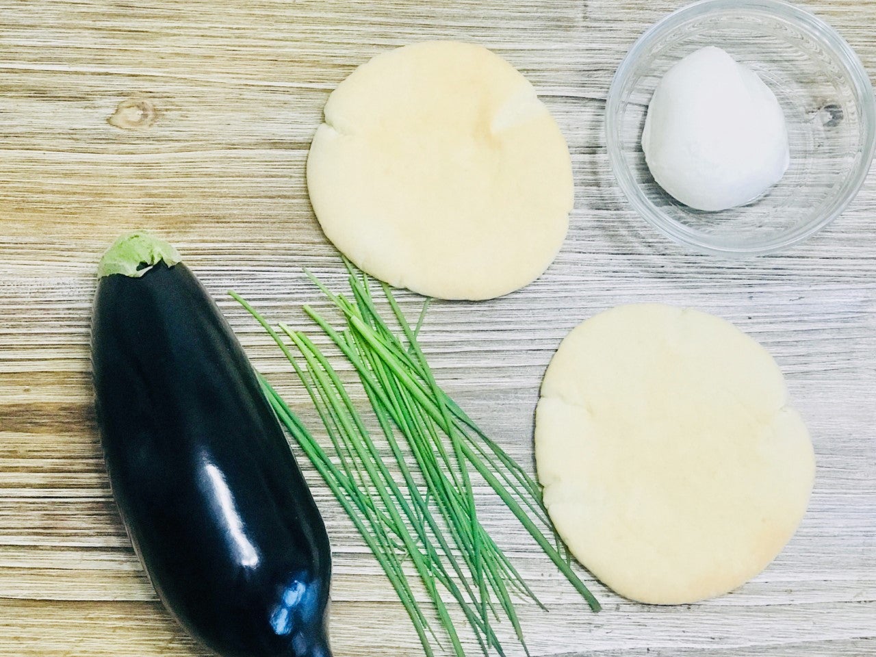 BERENJENA EN PAN DE PITA. Ingredientes: Berenjena, cebollino, mozzarella, sal, pimienta negra, aceite de oliva virgen extra y pan de pita. Cantidad según comensales.