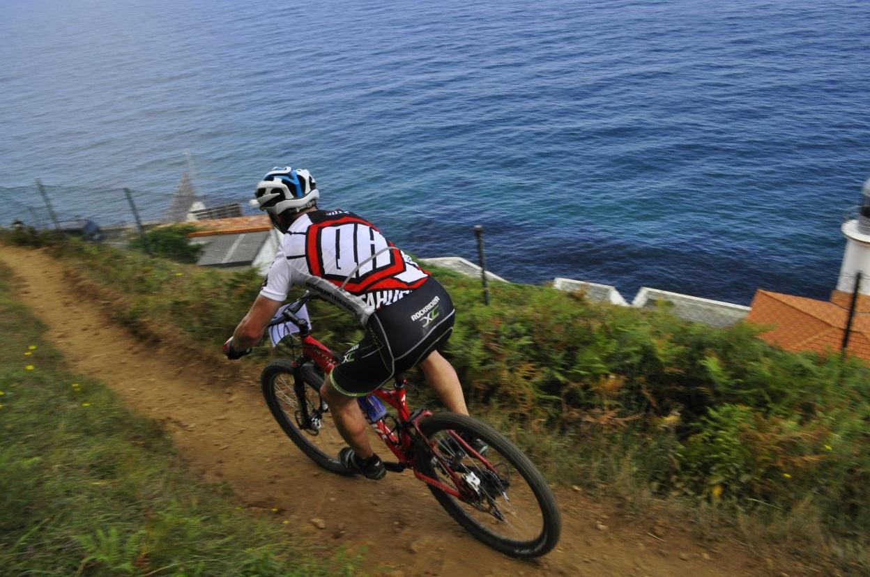 Un ciclista pasa por el Faro del Pescador. :: CTB