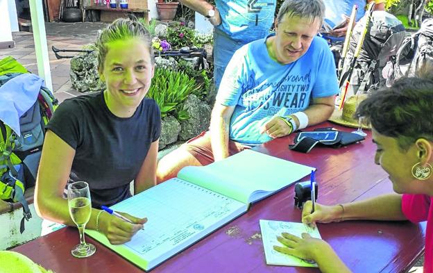 La joven alemana, Marianne Drews, se registra en el libro del albergue como la peregrina número 100.000 . 