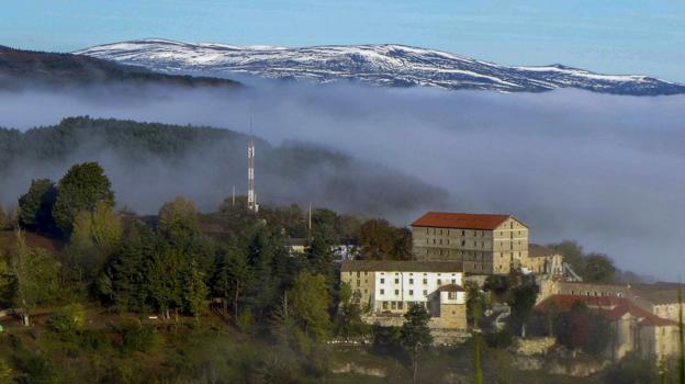 El santuario de Montesclaros, con la niebla sobre la zona del embalse y la cordillera al fondo