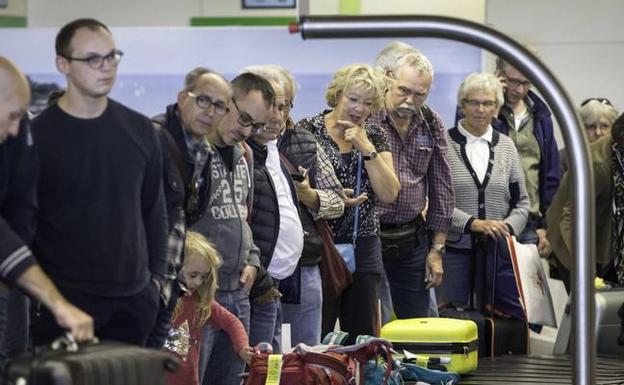 Pasajeros esperan sus maletas en el aeropuerto Seve Ballesteros 