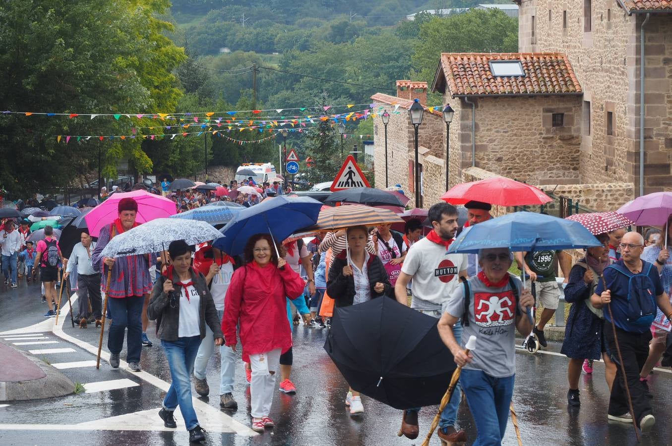 Los vecinos de Cartes tuvieron que sacar los paraguas para participar en el 'Día de las albarcas', caminando bajo la lluvia hasta Cohicillos