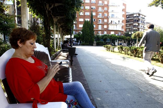 Una vecina utiliza su teléfono móvil en la Plaza de Pequeñeces. :