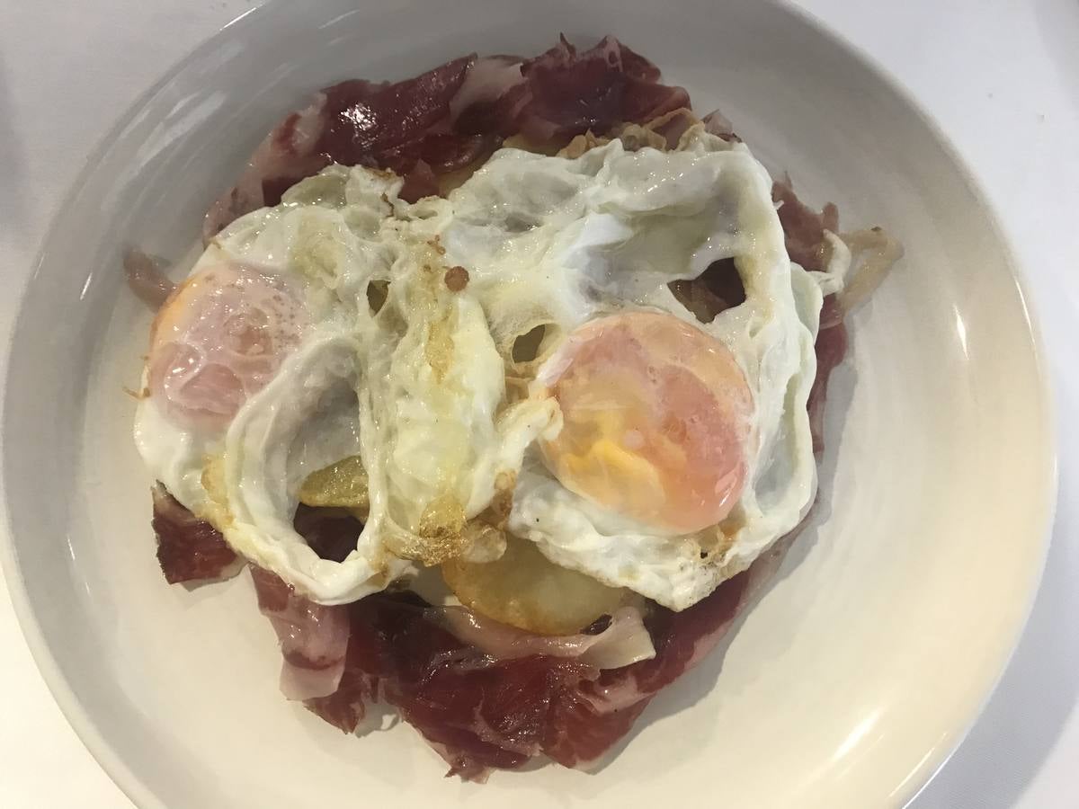 Imagen principal - Huevos de corral con patatas y jamón ibérico y ensaladilla rusa. Abajo, Mame Herrero y Raúl Ruiz.
