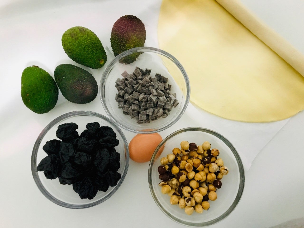 DULCE AGUACATE. Ingredientes: Masa Brisa, aguacate, ciruelas sin hueso, avellanas, pepitas de chocolate, un huevo. Para acompañar: chocolate de fundir. 