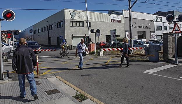 Viandantes y un ciclista atraviesan el paso a nivel del Paseo del Niño. 