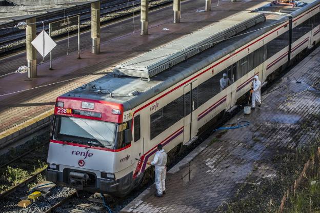 Varios operarios limpian un tren de Cercanías de Renfe en la estación de Santander. 