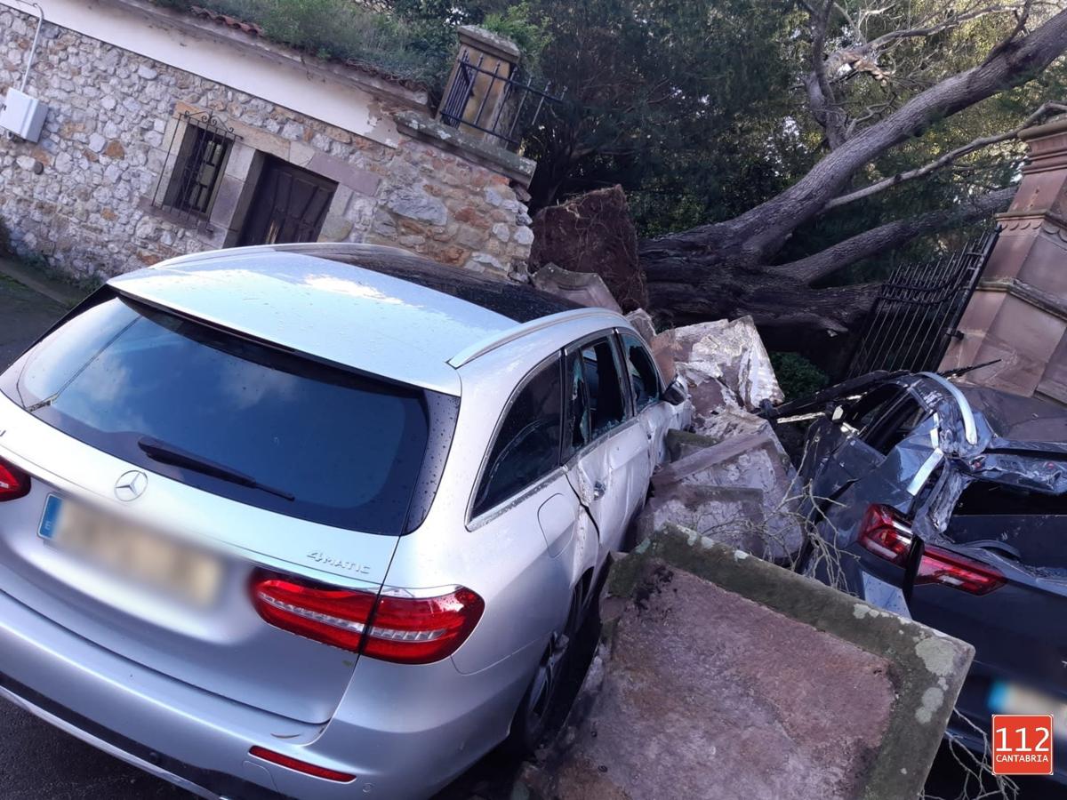 Un árbol de grandes dimensiones cayó sobre un muro y dos coches en Comillas.