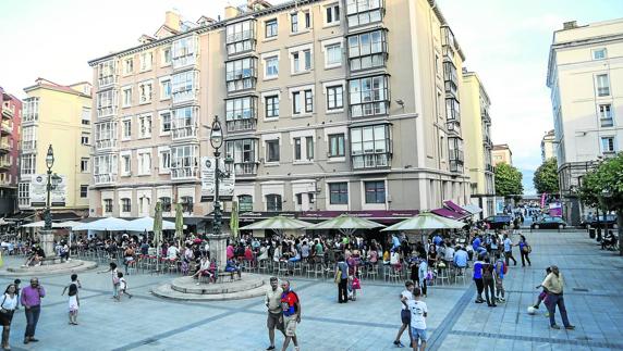 La plaza, con sus farolas artísticas, sus terrazas, los transeúntes y los niños jugando. 